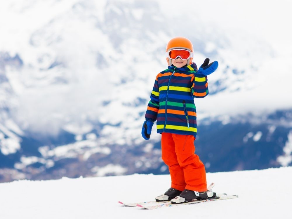 kind op ski's zwaait naar camera