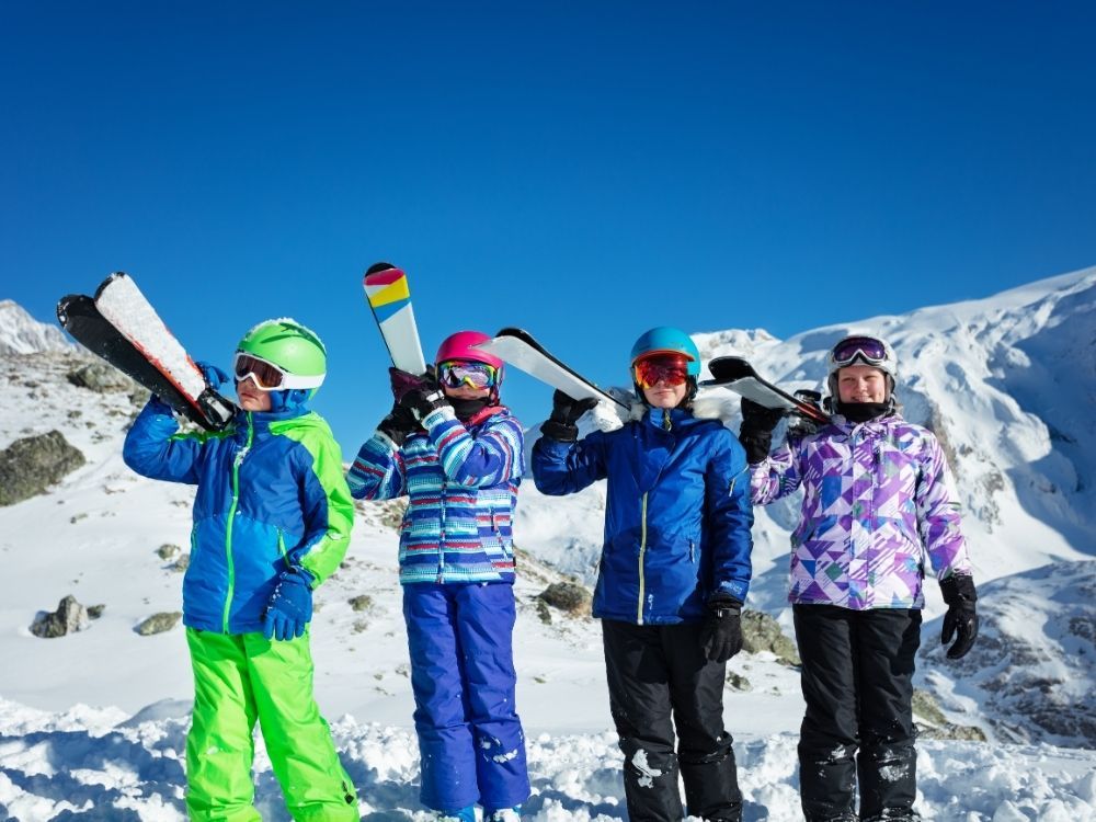 kinderen poseren met ski's op schouder