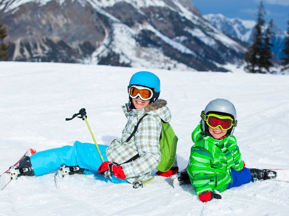 kinderen zitten in sneeuw met ski's aan